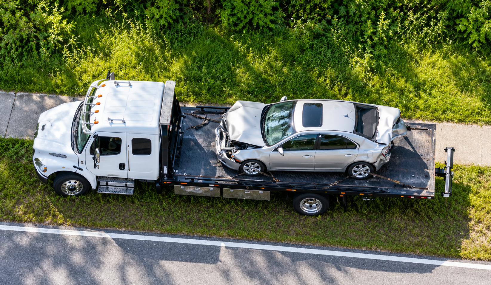 Tow truck transporting a wrecked sedan